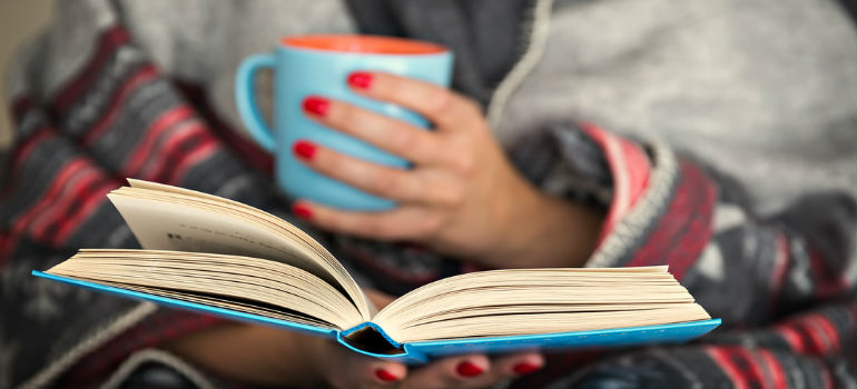 Woman drinking coffee and reading a book