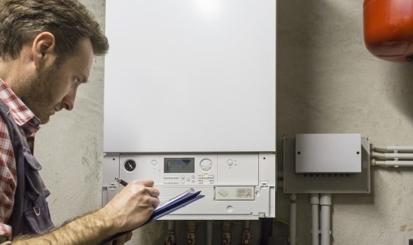 Gas-certified heating engineer who inspects a condensing boiler pipe leak