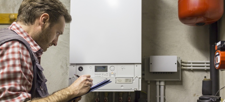 Gas-certified heating engineer who inspects a condensing boiler pipe leak
