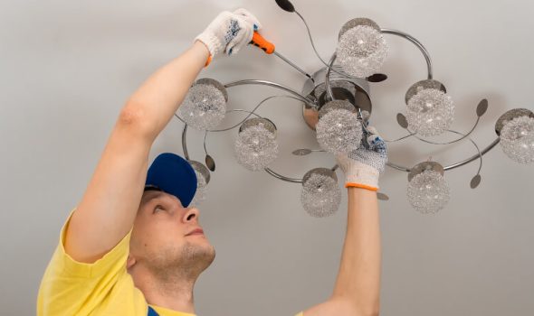 Electrician screws a chandelier to the ceiling close-up