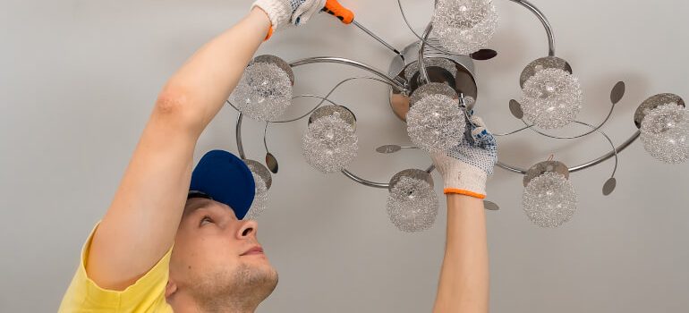 Electrician screws a chandelier to the ceiling close-up